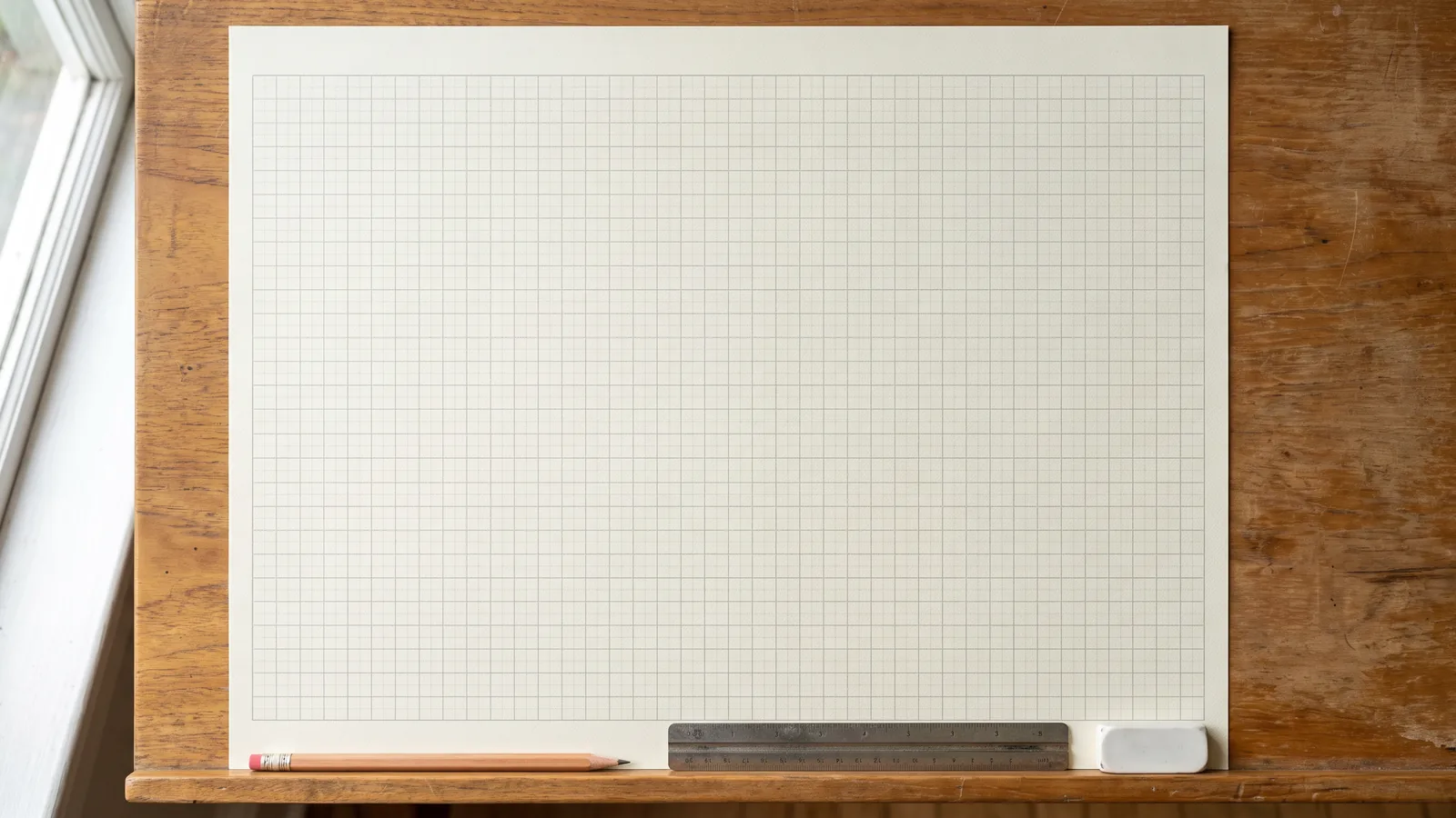 Une feuille de papier millimétré vierge avec un crayon, une règle et une gomme