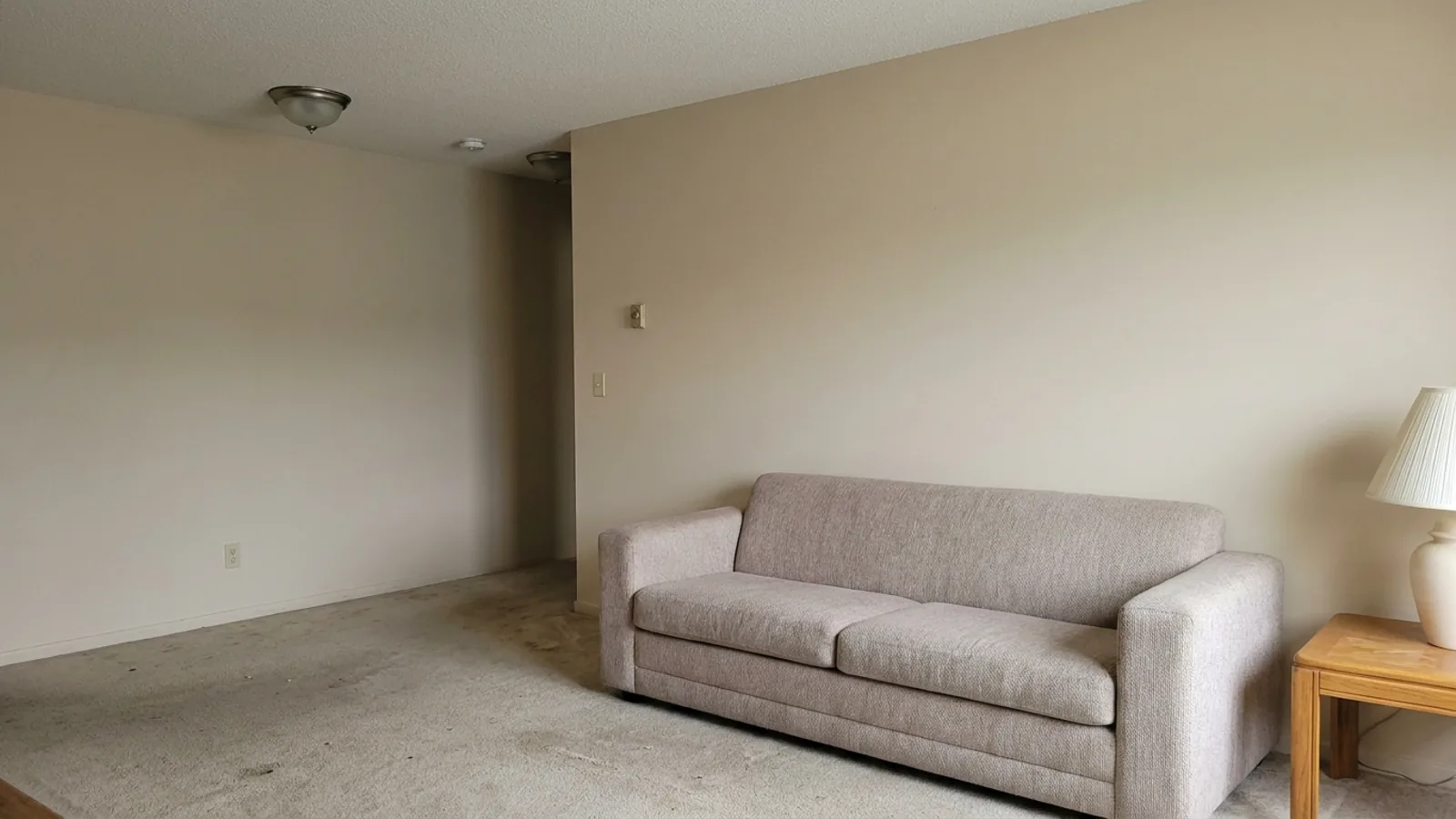 Un salon beige fade avec un canapé imposant